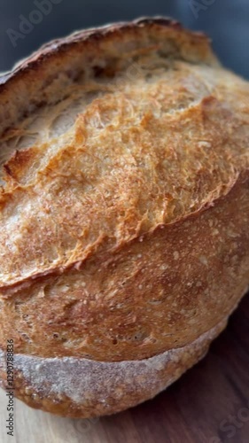 Artisan bread in close-up, showcasing its crunchy crust and warm golden tones. White mica dust adds texture against the dark backdrop, enhancing the fresh, homemade appeal