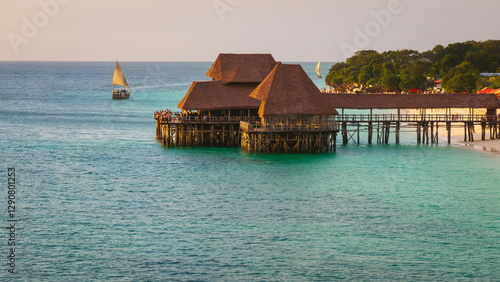 Thatch stilt house restaurant at Kendwa beach at sunset,drone view of turquoise ocean and dhow boat on the ocean,Kendwa beach at Zanzibar,Tanzania. photo