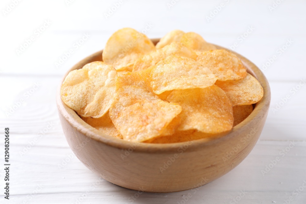 Tasty potato chips in bowl on white wooden table, closeup Tasty potato chips in bowl on white wooden table, closeup
