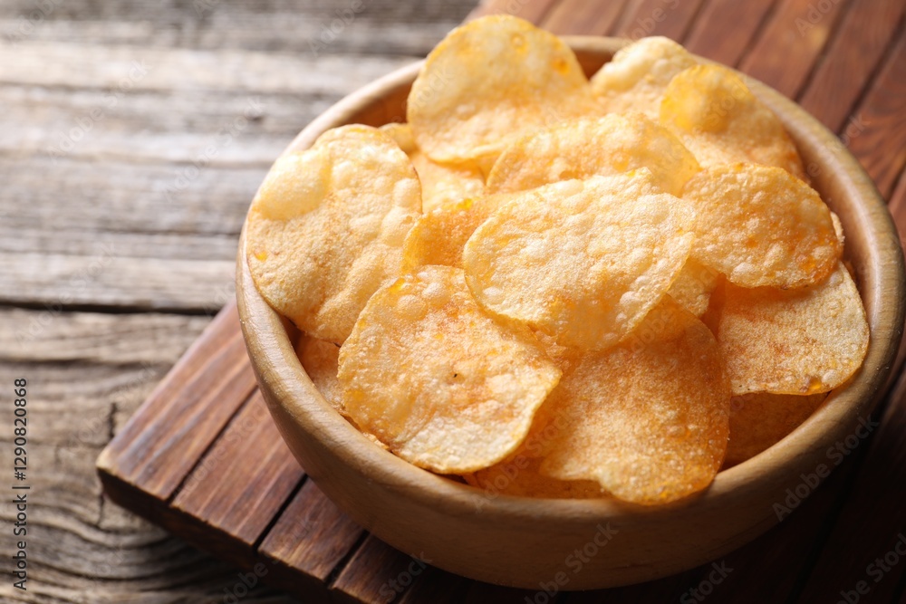 Tasty potato chips in bowl on wooden table, closeup Tasty potato chips in bowl on wooden table, closeup