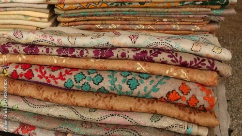 Wallpaper Mural Beautiful Handloom Shawls, Colorful embroidered textile with geometric and floral patterns, Colorful patterned fabrics hanging outdoors at a market.  Torontodigital.ca