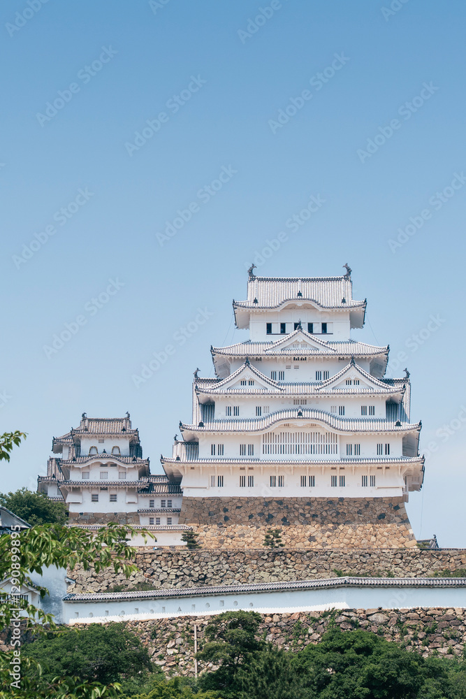 A direct front-facing view of Himeji Castle's main keep, showcasing its multi-tiered white walls, stone base, and intricate traditional Japanese architectural elements. A direct front-facing view of Himeji Castle's main keep, showcasing its multi-tiered white walls, stone base, and intricate traditional Japanese architectural elements.
