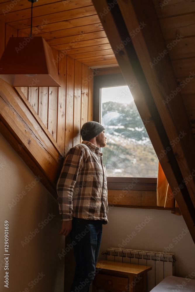 Man in cozy cabin looking out snowy window Man in cozy cabin looking out snowy window
