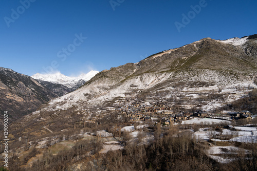 Village nestled in expansive mountainous landscape with snow photo