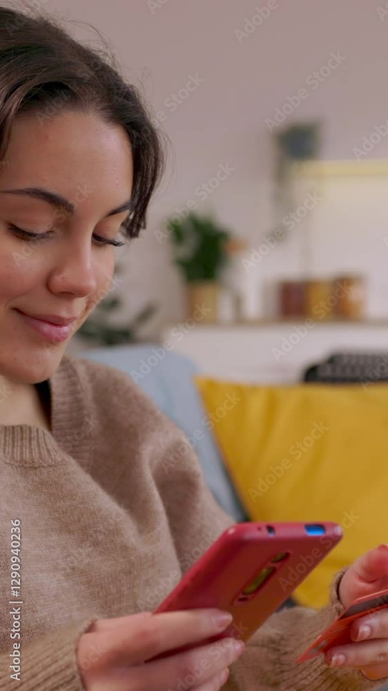 Vertical HD video of young woman holding smart phone and credit card, making online payment on e-commerce platform at home Vertical HD video of young woman holding smart phone and credit card, making online payment on e-commerce platform at home