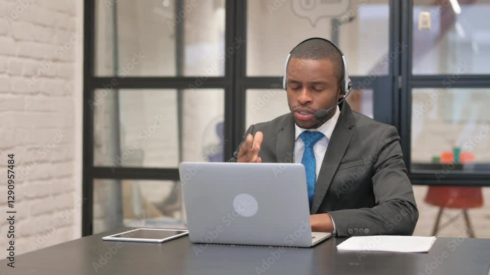 African Businessman with Headset Doing Video Chat via Laptop African Businessman with Headset Doing Video Chat via Laptop