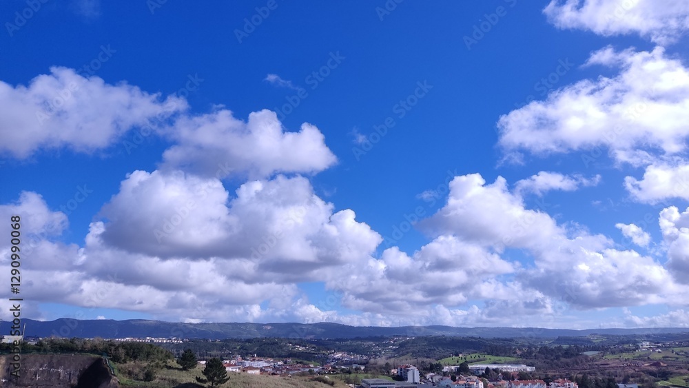 Stunning panoramic view of a picturesque landscape under a vibrant blue sky adorned with fluffy cumulus clouds. Stunning panoramic view of a picturesque landscape under a vibrant blue sky adorned with fluffy cumulus clouds.