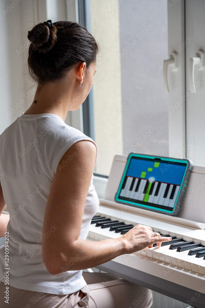 Young woman learning to play the keyboard at home using an interactive app. Using mobile apps for self-study concept Young woman learning to play the keyboard at home using an interactive app. Using mobile apps for self-study concept