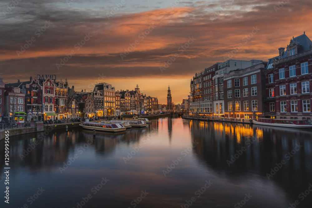 Amsterdam, The Netherlands - 13 April 2022: View of charming houses at water canal with vibrant reflections and historic buildings, Amsterdam, The Netherlands. Amsterdam, The Netherlands - 13 April 2022: View of charming houses at water canal with vibrant reflections and historic buildings, Amsterdam, The Netherlands.