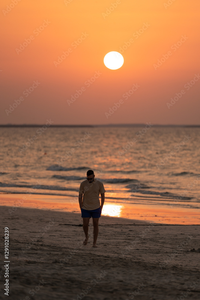 Tourist man walking on the beach at sunset enjoying golden hour Tourist man walking on the beach at sunset enjoying golden hour