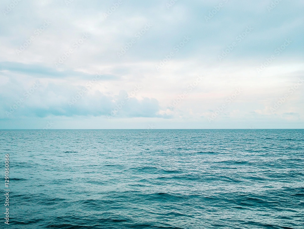 Obraz premium A peaceful view of the endless ocean meeting the sky, with gentle waves and soft clouds creating a calming and tranquil seascape