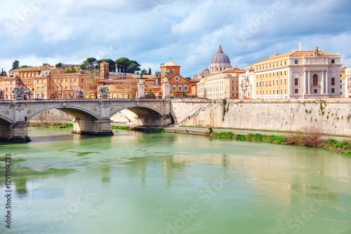 Obraz na płótnie Scenic view of Ponte Vittorio Emanuele over Tiber River, with St. Peter Basilica rising in background in Rome Italy. Historic architecture, dramatic clouds, and reflections create timeless atmosphere w salonie