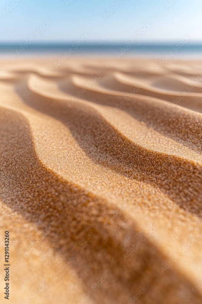 Close-up of wavy sand texture on a beach with a blurred ocean background. Warm, golden tones. Close-up of wavy sand texture on a beach with a blurred ocean background. Warm, golden tones.