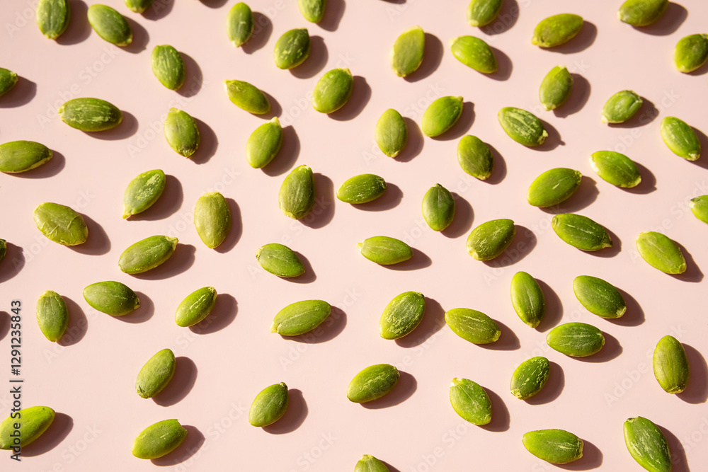 Peeled pumpkin seeds on pink surface. Peeled pumpkin seeds on pink surface.