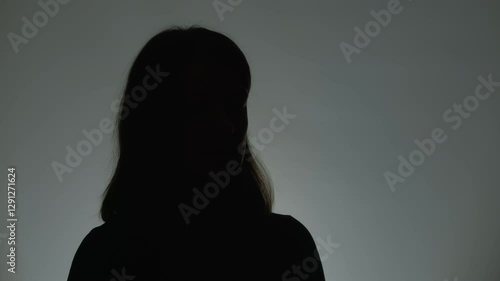 Anonymous interview with a woman who suffered from violence. Female silhouette. Hidden person speaking in a dark studio.
