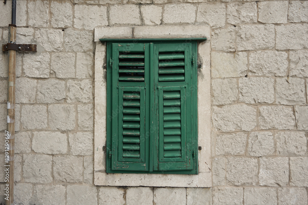 Traditional Croatian house window. Wooden green shutters. White bricks wall. Outdoors. Tourism. Traditional Croatian house window. Wooden green shutters. White bricks wall. Outdoors. Tourism.