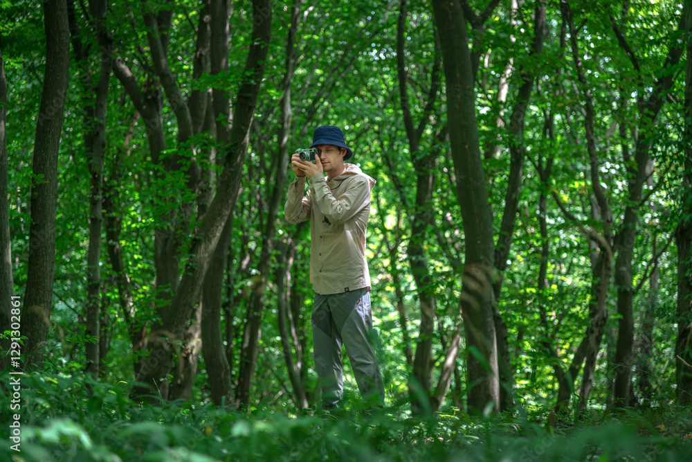 The portrait of a handsome man going to take a picture on his camera while hiking in a forested mountain area in the spring-summer time The portrait of a handsome man going to take a picture on his camera while hiking in a forested mountain area in the spring-summer time