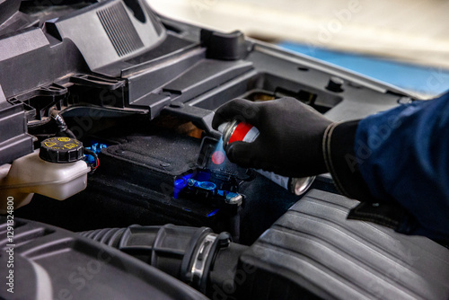 Cleaning the car battery terminal from dirt and oxidation. Car service, repair concept. Spraying with a special agent parts under the hood of the car