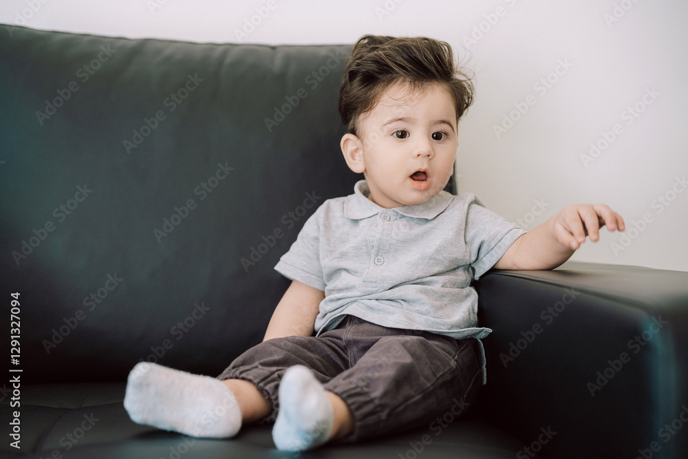 Adorable Toddler Sitting on Couch With Surprised Expression in Casual Attire Adorable Toddler Sitting on Couch With Surprised Expression in Casual Attire
