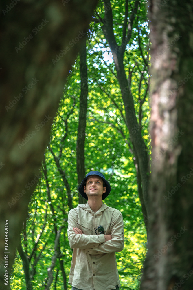 Portrait of a handsome man with a camera and crossed arms, standing confidently in a forested mountain area during spring or summer. Portrait of a handsome man with a camera and crossed arms, standing confidently in a forested mountain area during spring or summer.