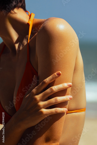 Close-up of female asian adult sunbathing on the beach in orange bikini. Skin care, sun protection