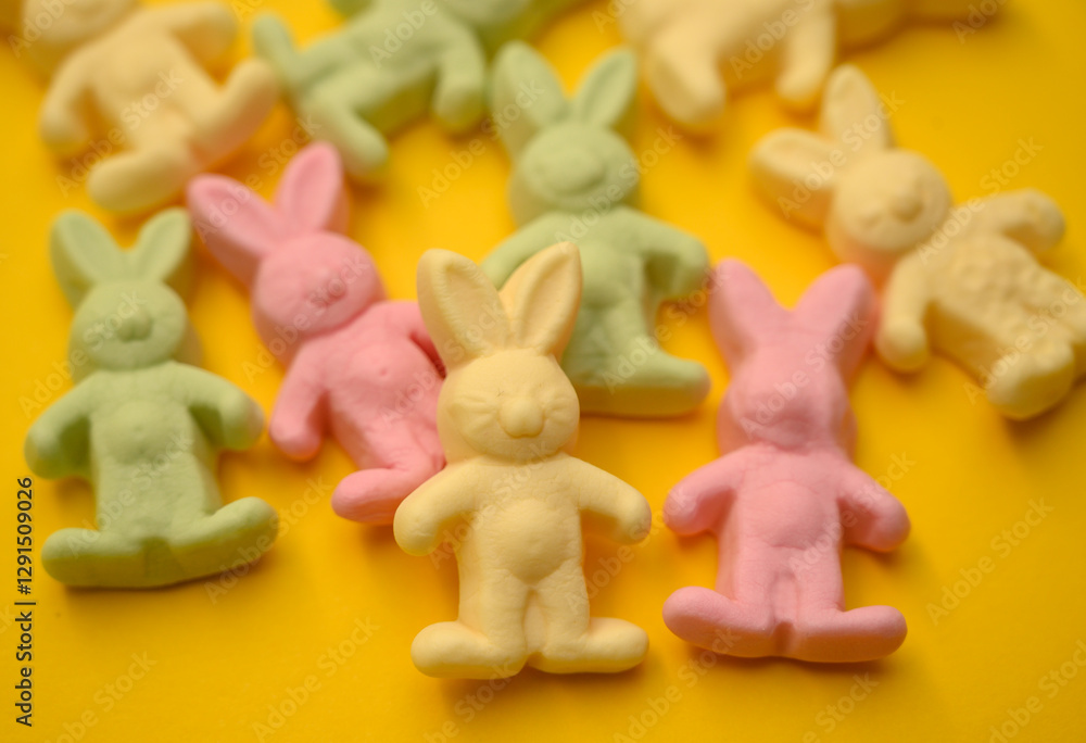 Naklejka premium A collection of pastel bunny-shaped gummy candies on a bright yellow background. Perfect for Easter, holiday decorations, and festive spring-themed designs.
