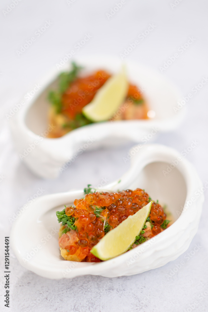 Salmon tartare appetizer with caviar. Mini tartlets with red salmon caviar and smoked salmon, an appetizer idea for a festive table Salmon tartare appetizer with caviar. Mini tartlets with red salmon caviar and smoked salmon, an appetizer idea for a festive table