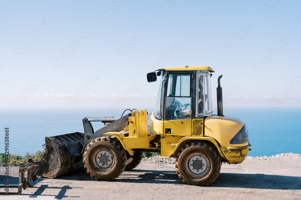 Yellow excavator stands on a steep seashore. Side view Yellow excavator stands on a steep seashore. Side view