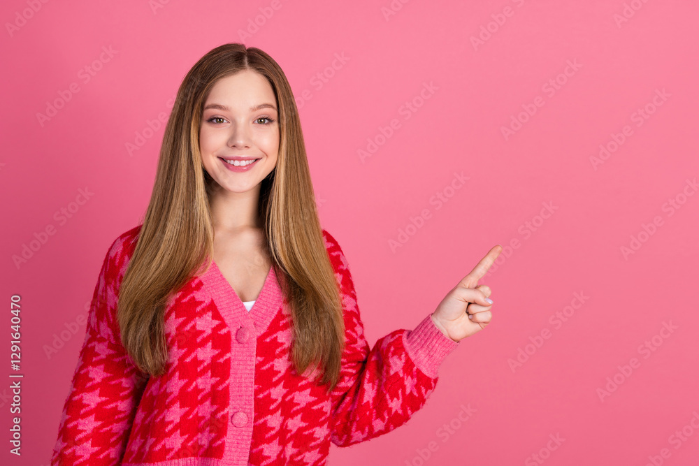 Young woman in fashionable pink cardigan with a cheerful smile pointing to the side on a vibrant pink background Young woman in fashionable pink cardigan with a cheerful smile pointing to the side on a vibrant pink background