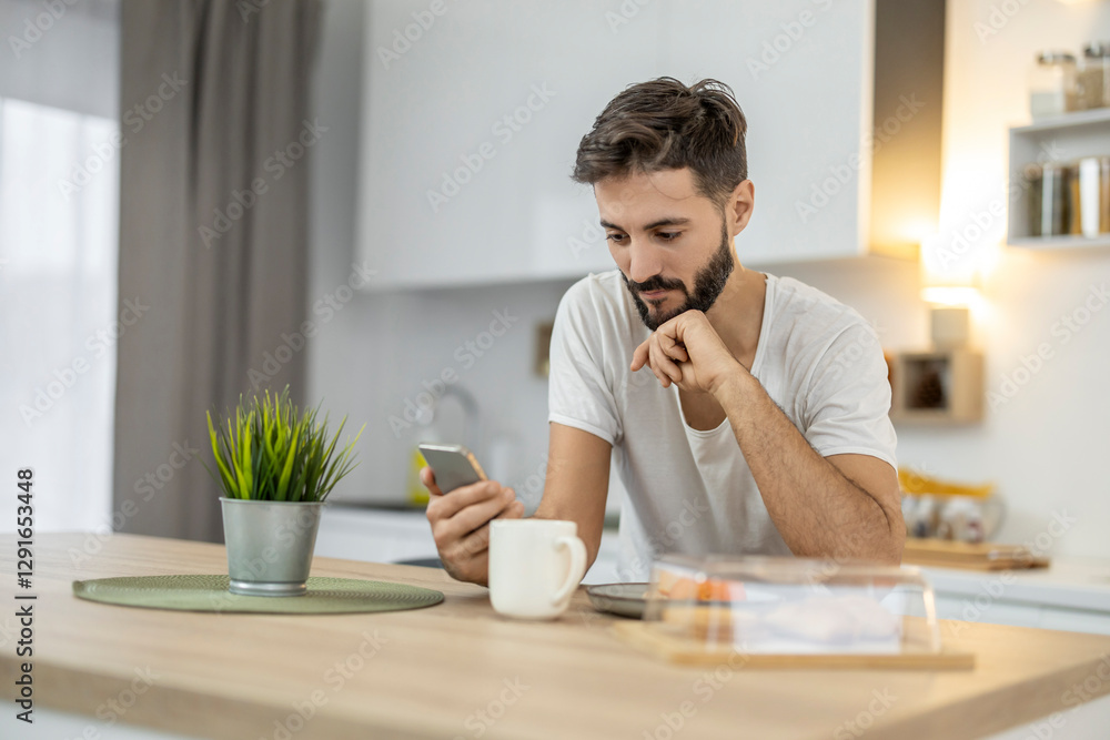 Man relaxing in modern kitchen while checking phone and enjoying coffee in a cozy morning atmosphere Man relaxing in modern kitchen while checking phone and enjoying coffee in a cozy morning atmosphere