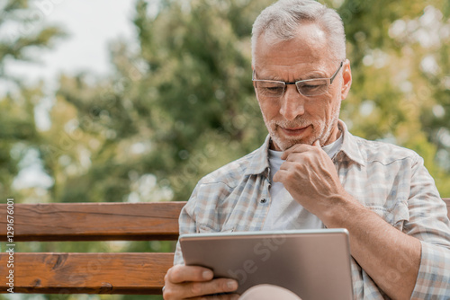 Foto Smiling modern old man in casual eyeglasses relaxing city park