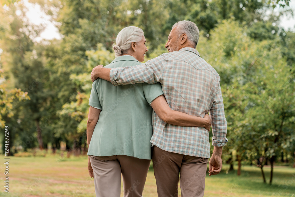 Rear view of senior couple walking outdoors in summer park and embracing, loving happy mature spouses hugging and smiling to each other, cheerful husband and wife enjoying outside walk, copy space Rear view of senior couple walking outdoors in summer park and embracing, loving happy mature spouses hugging and smiling to each other, cheerful husband and wife enjoying outside walk, copy space