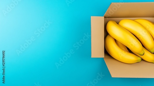 Bananas in cardboard box on teal background photo