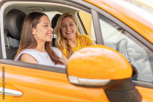 Obraz na płótnie Two happy women sit in a yellow car, smiling and laughing together, capturing the spirit of friendship, joy, and the excitement of a road trip. w salonie