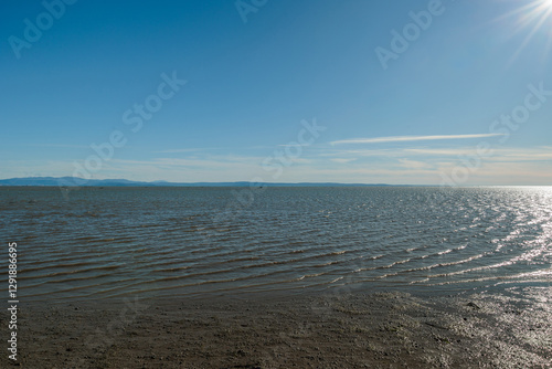 Obraz na płótnie vista che si estende sull'area marina del Golfo di Trieste, nel mare Adriatico, guardando verso le colline e le montagne distanti tra Italia e Slovenia, di giorno, con cielo sereno, in inverno w salonie