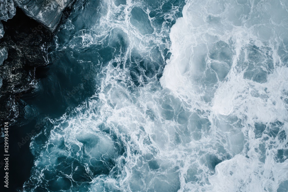 Fototapeta premium Foaming ocean water flows with dark rocks along the coast