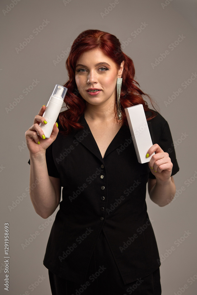 Elegant woman holding skincare product, white bottle, red hair, black dress, beauty care, confident expression, skincare concept