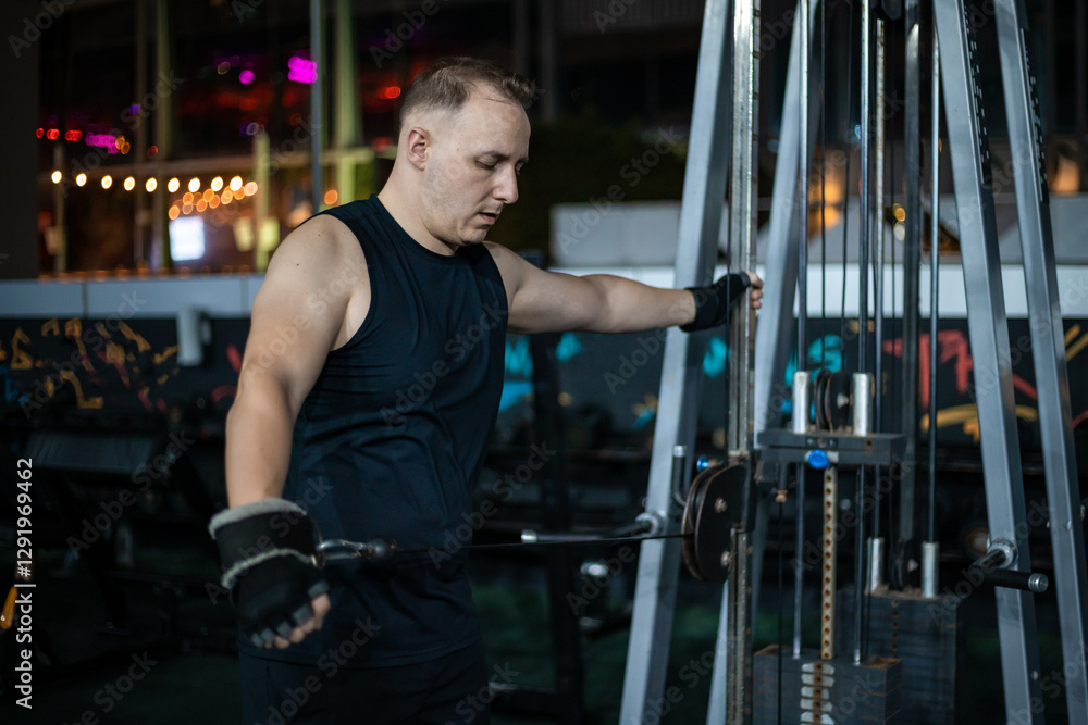 Man Working Out On Cable Machine At Gym Man Working Out On Cable Machine At Gym