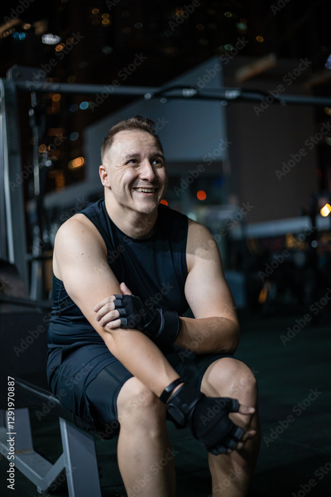 Smiling Man Wearing Gloves While Resting on a Bench at the Gym Smiling Man Wearing Gloves While Resting on a Bench at the Gym