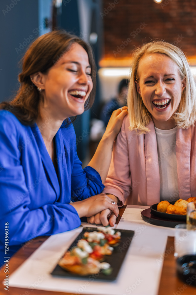 Fototapeta premium Smiling lesbian couple talking to each other at restaurant.