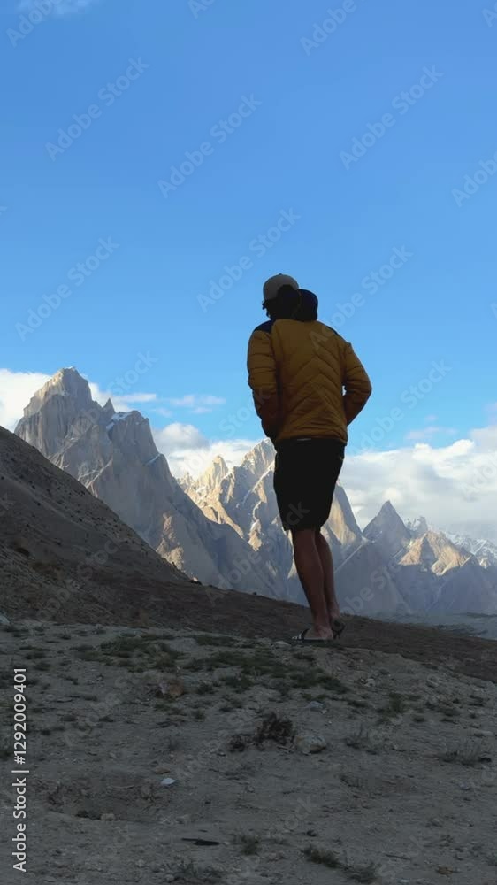 Majestic view of trango towers in karakoram, pakistan, with a hiker contemplating the landscape Majestic view of trango towers in karakoram, pakistan, with a hiker contemplating the landscape