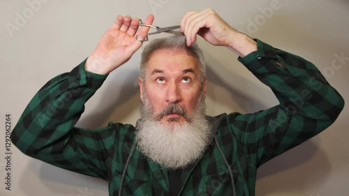 A senior man with a wild grey beard playfully mimics cutting his own hair using large silver scissors. Neutral backdrop, expressive face, plaid shirt. Perfect for comedy, social media, or ads about ag