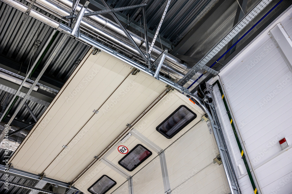 Fototapeta premium View of automatic sectional garage door from inside. hall gate in logistics warehouse from inside - Ramp gate