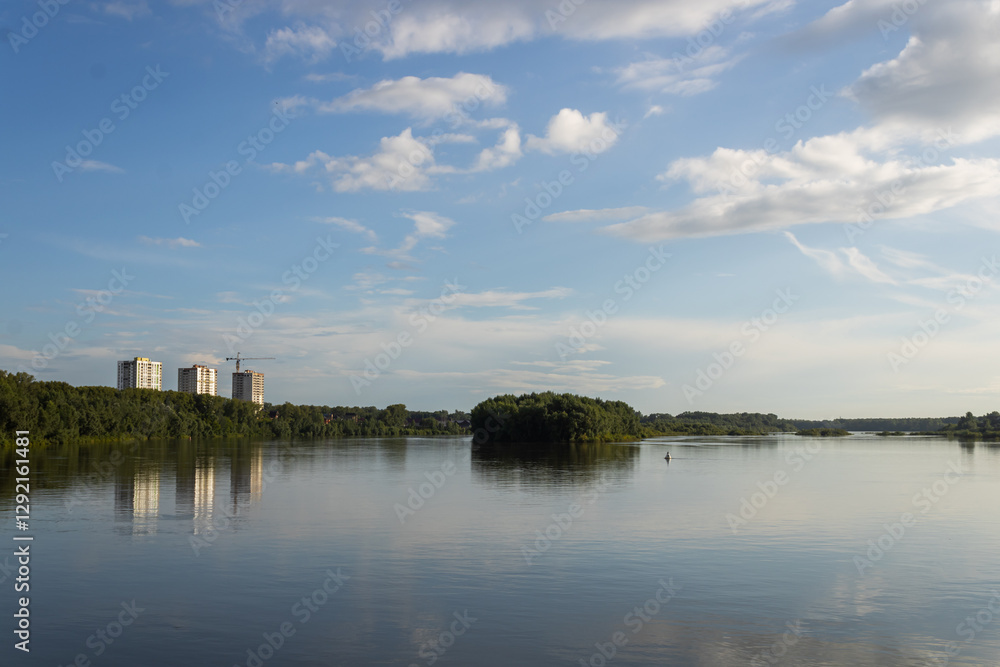 River, green island, trees on the embankment, houses under constructionand cranes. Cloudy sky on a sunny day. The capital of Bashkiria, the city of Ufa River, green island, trees on the embankment, houses under constructionand cranes. Cloudy sky on a sunny day. The capital of Bashkiria, the city of Ufa