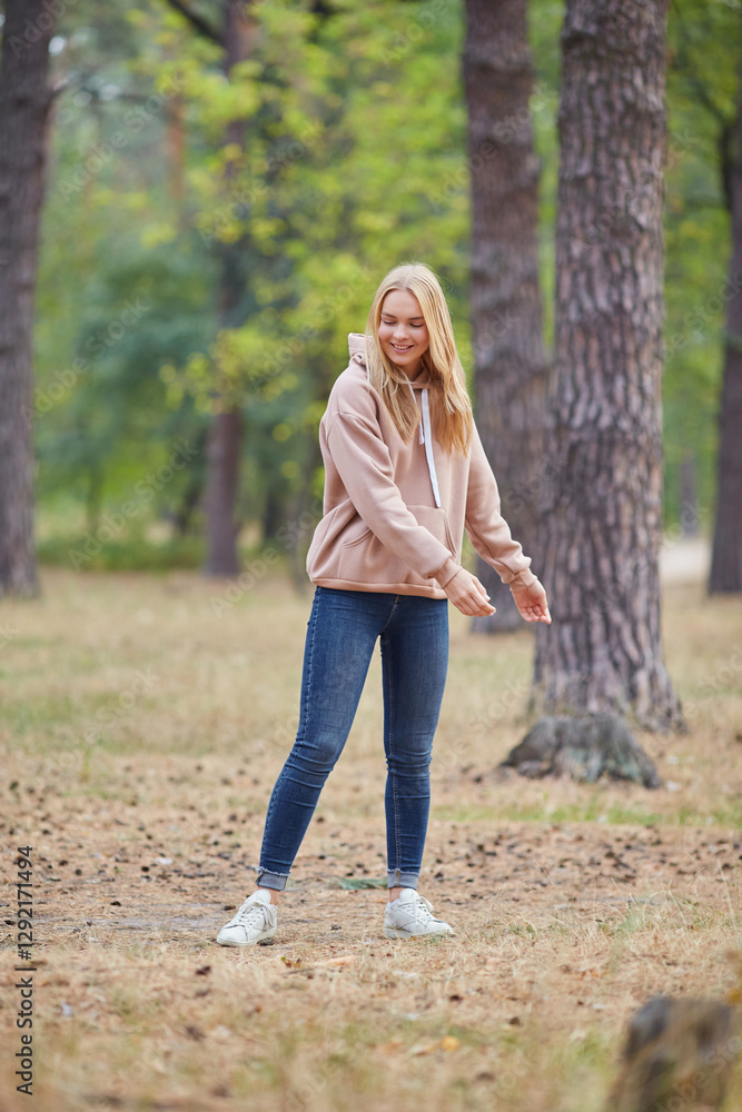 Attractive blue eyed blonde woman walk on the city park. Girl wear beige hoodie, pink bag and look happy and smiles. Attractive blue eyed blonde woman walk on the city park. Girl wear beige hoodie, pink bag and look happy and smiles.