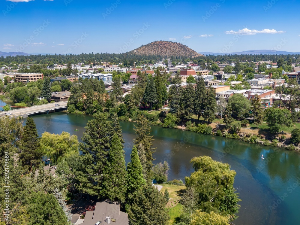 Fototapeta premium Aerial view of Drake Park, Bend, town, river, and a kayaker. Sunny day, city park, and a bridge. Peaceful scene. Bend, Oregon, USA