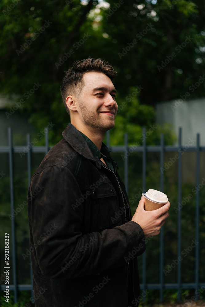 Vertical side view of happy relaxed young man in casual attire, holding coffee cup, enjoying peaceful break outdoors, radiating calm and contentment in urban setting. Concept of urban lifestyle. Vertical side view of happy relaxed young man in casual attire, holding coffee cup, enjoying peaceful break outdoors, radiating calm and contentment in urban setting. Concept of urban lifestyle.