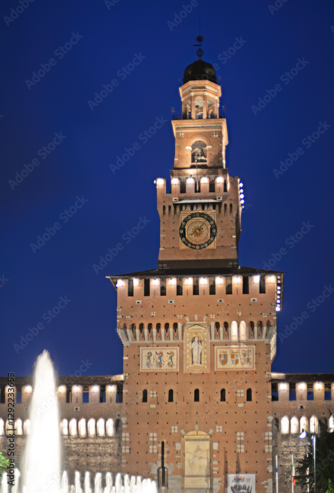 Obraz premium Castello Sforzesco (Sforza Castle) tower on Piazza Castello with fountain in front of Castello Sforzesco (Sforza Castle) in Milan, Italy, in the evening with dark blue sky