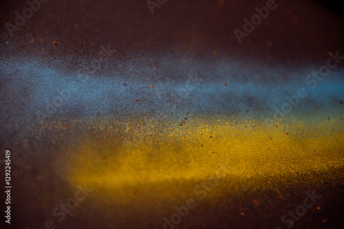 Close-up of a textured surface featuring blue and yellow spray paint blending together, creating an abstract and artistic effect with scattered particles. Ukraine flag