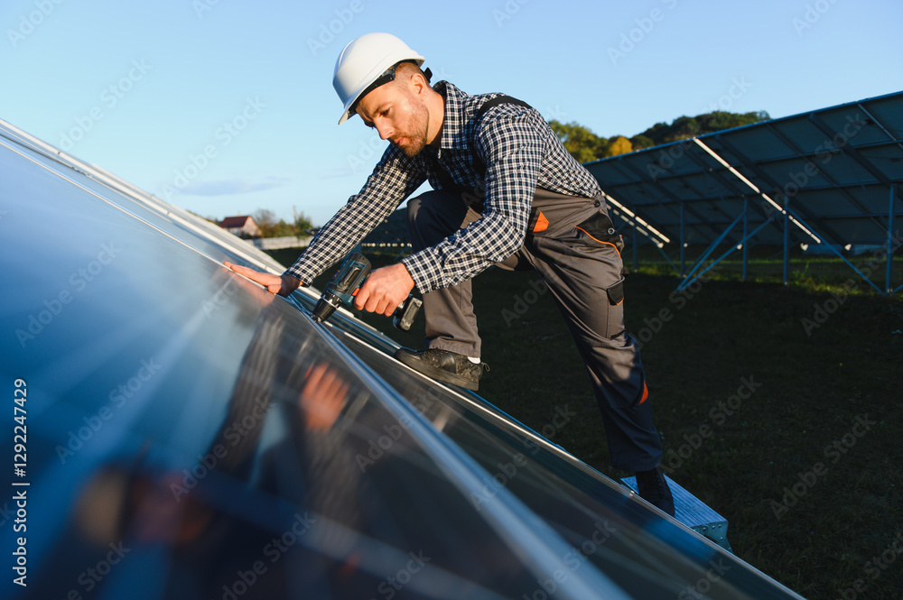 Worker installing solar panel on metal beams at sunny daytime. Renewable and ecological energy. Idea of environment safe. Modern technology and innovation. Man wearing workwear and helmet Worker installing solar panel on metal beams at sunny daytime. Renewable and ecological energy. Idea of environment safe. Modern technology and innovation. Man wearing workwear and helmet